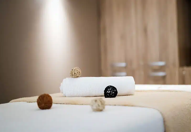 reiki-800 Entspannungsliege mit Handtuchrolle und ausgebreitetem Handtuch und einen Dekokugeln in einer warmen, sanften Atmosphäre