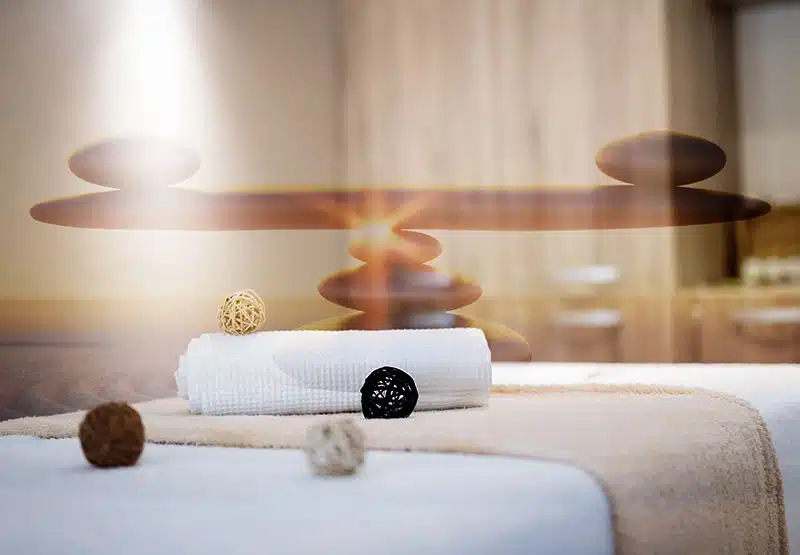 Steine die als Balancesymbol liegen, eine Reikiliege mit Handtüchern
